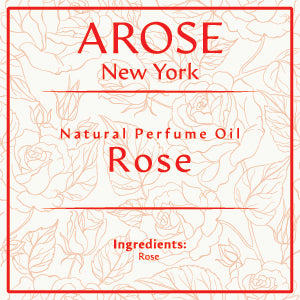 10ml roll-on bottle of Arose NY Rose Perfume Oil placed elegantly with fresh rose petals – alcohol-free, unisex fragrance for everyday wear.
